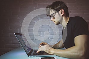 Handsome young programmer working at home late in evening