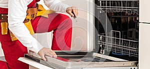 handsome young repairman fixing oven with screwdriver