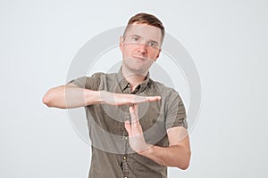 Handsome young serious man, coach showing time out gesture with hands, isolated on white background.