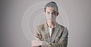 Handsome young serious man in isolated over grey wall background. Studio shot of young caucasian man with arms crossed