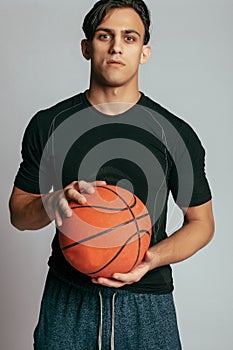 Handsome young smiling man carrying a basketball ball