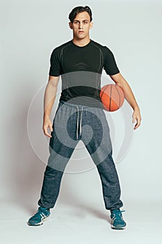 Handsome young smiling man carrying a basketball ball