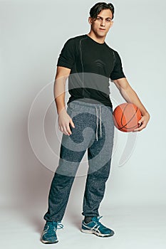 Handsome young smiling man carrying a basketball ball