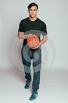 Handsome young smiling man carrying a basketball ball