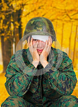 Handsome young soldier wearing uniform suffering from stress, with a white bandage around his head and covering his eye