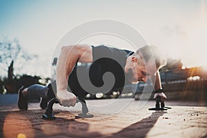 Handsome young sport man doing pushups in the park on the sunny morning.Healthy lifestyle concept.Training outdoors