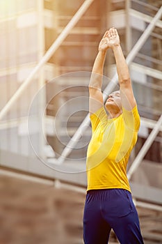 Handsome young sport man in sportswear stretching while warming up in city outdoor . morning