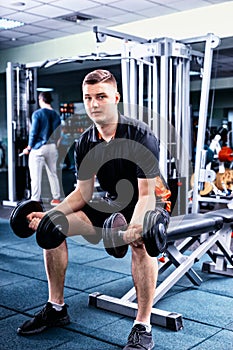 Handsome young sportive man in sportswear lifting some weights