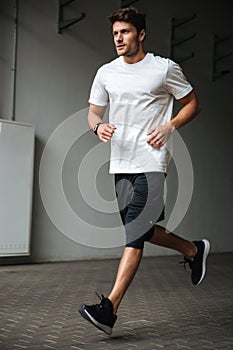 Handsome young sports man running at the stadium