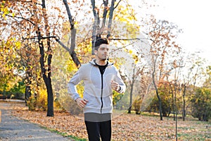 Handsome young sportsman outdoors in park listening music with earphones running