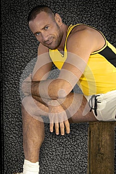 A handsome young and stubble bearded athlete stretches in a relaxed pose for his sport portrait.