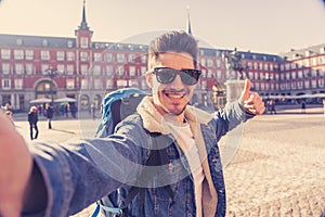 Handsome young student tourist man happy and excited taking a selfie in Madrid, Spain