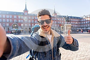 Handsome young student tourist man happy and excited taking a selfie in Madrid, Spain