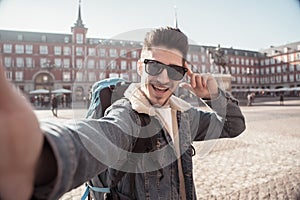 Handsome young student tourist man happy and excited taking a selfie in Madrid, Spain