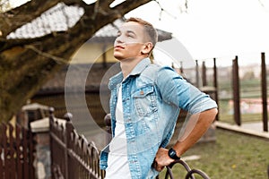 Handsome young stylish man in a jeans jacket and a white T-shirt is enjoying the moment and looking up