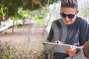Handsome young teenager boy use laptop device oudoor with garden in background - technology and leisure activity for younger
