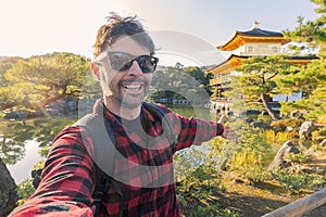 Handsome young tourist enjoying summer holiday in Kyoto, Japan - Traveling life style concept with smiling man taking selfie on