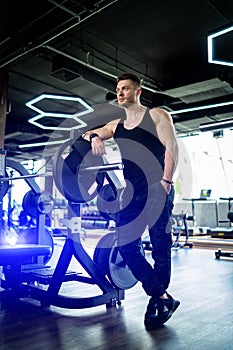 Handsome young trainer posing for camera in gym. Athlete workout muscular trainer.