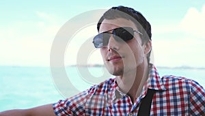 Handsome young traveler man in sunglasses enjoying sailing boat on sea. slow motion. 3840x2160