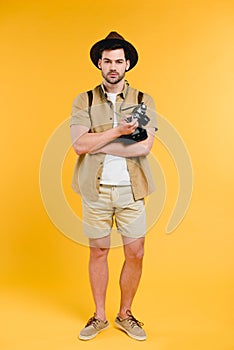 Handsome young traveler in shorts and hat holding camera