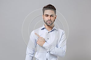 Handsome young unshaven business man in light shirt posing isolated on grey background studio portrait. Achievement