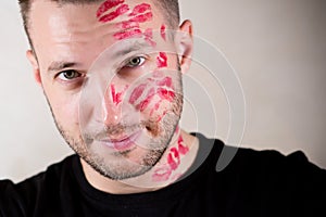 Handsome young unshaven man with traces of kisses on his half face