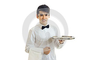 Handsome young waiter`s shirt smiles and stretches forward the empty tray for eating