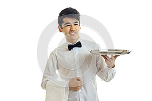 Handsome young waiter stretches forward tray for cupboards and smiling