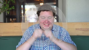 Handsome young white fat happy man waiting for something with great intrigue in restaurant