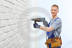 Handsome young working man using rotary hammer. Home repair