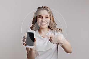 Handsopme young woman holding white iphone isolated over the white background