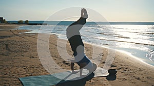 Handstand yoga pose by man on the beach near the ocean