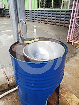 The handwashing basin is created by utilizing a blue oil drum, typically used for storing oil or other liquids.