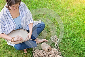 Handwork hobby Woman is crocheting a basket from a thick cord from eco friendly materials on the grass in the garden