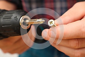 Handworker working with an electric screwdriver. Carpenter fixing wooden construction with portable drill