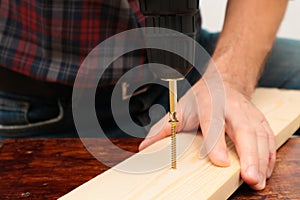 Handworker working with an electric screwdriver. Carpenter fixing wooden construction with portable drill