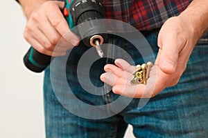 Handworker working with an electric screwdriver. Carpenter fixing wooden construction with portable drill