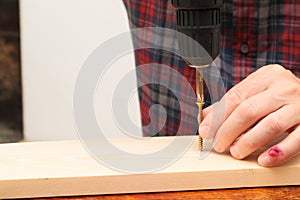 Handworker working with an electric screwdriver. Carpenter fixing wooden construction with portable drill