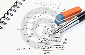 Handwriting of mathematics quadratic equation formula on examination, practice, quiz or test in math class.