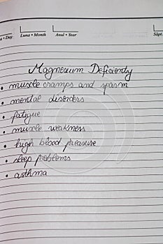 Handwriting text magnesium deficiency symptoms on page of office agenda. Copy space