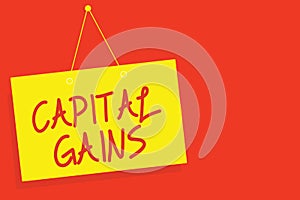 Handwriting text writing Capital Gains. Concept meaning Bonds Shares Stocks Profit Income Tax Investment Funds Yellow board wall m