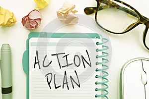 Handwritten ACTION PLAN text on a notebook with some office supplies