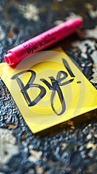 Handwritten Bye! farewell message on a yellow sticky note with pink marker, symbolizing parting, goodbyes, end of