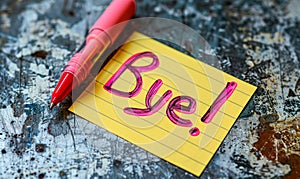 Handwritten Bye! farewell message on a yellow sticky note with pink marker, symbolizing parting, goodbyes, end of