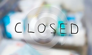 Handwritten closed shop sign with blurred products background