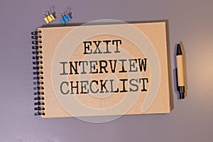 Handwritten Exit Interview Checklist Message On Notebook With Blue Marker And Spectacles Over Office Desk.