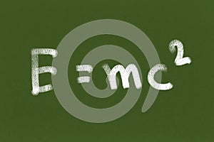 Handwritten formula E=mc2 on Green chalkboard or blackboard texture. illustration physics massÃ¢â¬âenergy equivalence formula. Back photo