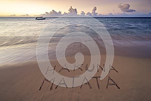 Handwritten Hakuna Matata on sandy beach at sunset african beach
