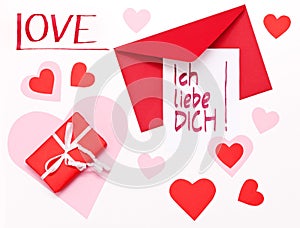 Handwritten Ich-liebe-Dich-note German for Valentine`s Day lying on a red envelope, next to a red parcel, surrounded by red and