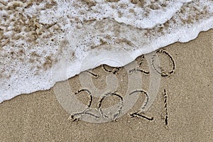 Handwritten inscription 2020 and 2021 on beautiful golden sand beach.